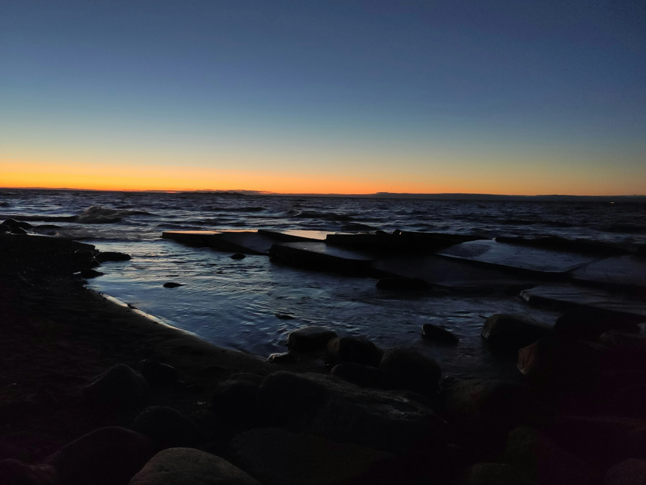 the setting sun reflects in the water and rocks