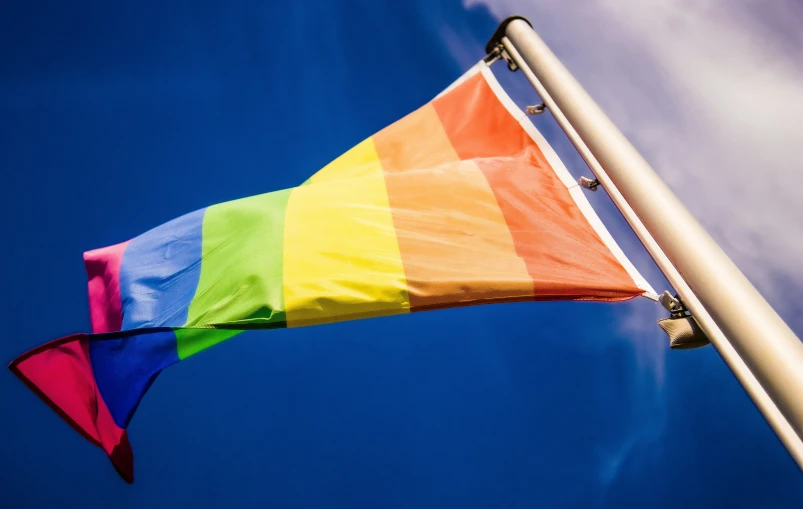 the rainbow colored kite flying high in the air