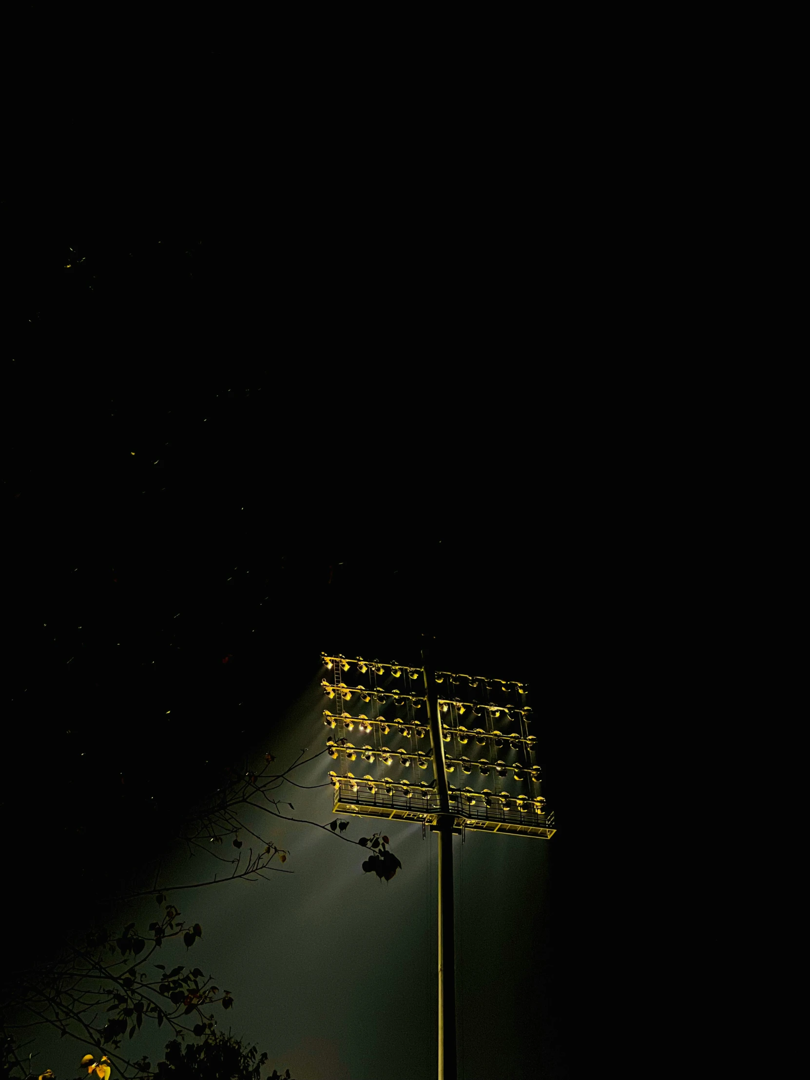 an illuminated football stadium in the dark with dark clouds