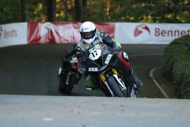 motorcycle racers in race on racetrack with cones and trees