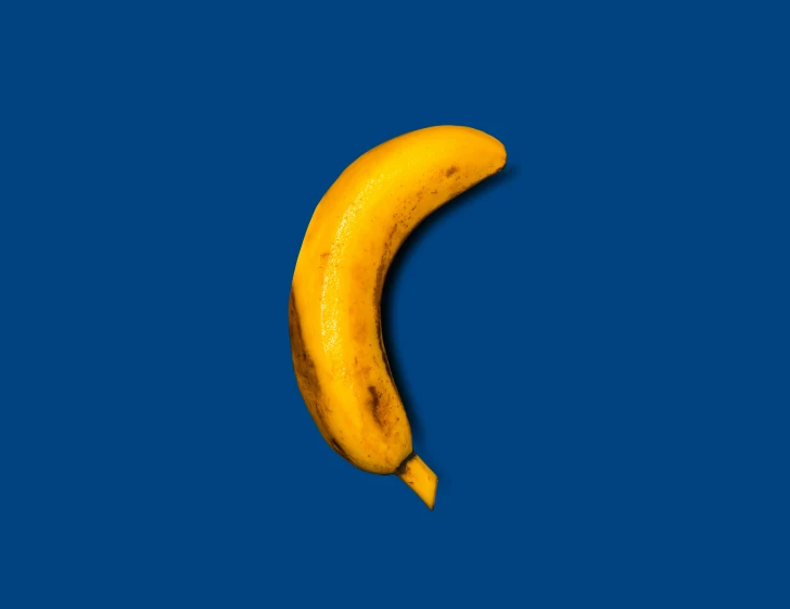 a single banana on a blue background is shown