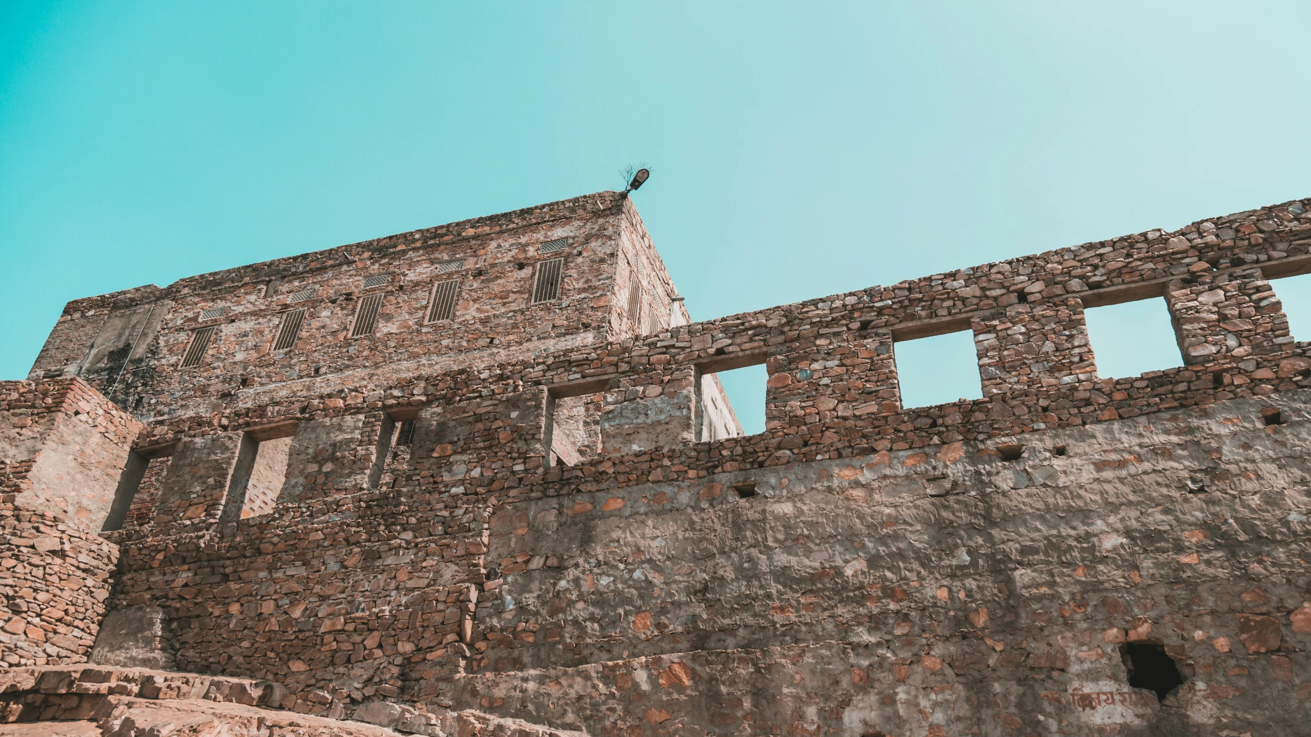 a bird perches on the top of an ancient brick tower