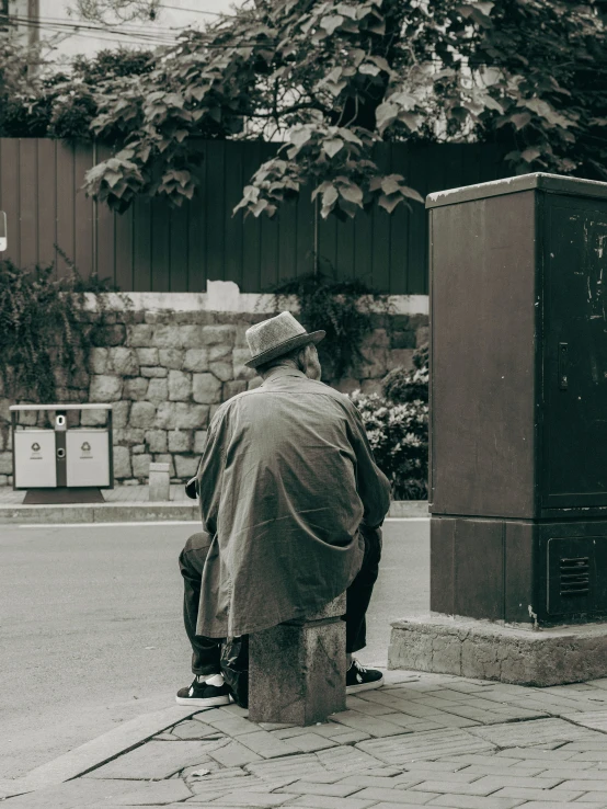 an old man sitting on a post next to a tree