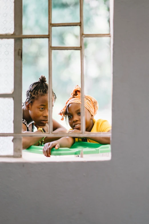 two small children look out the window of a small white building