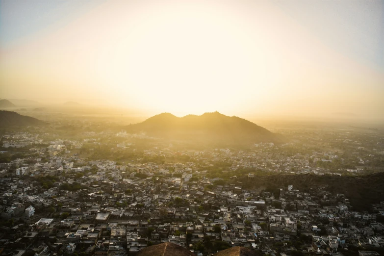 the sun shining behind a mountain over a city