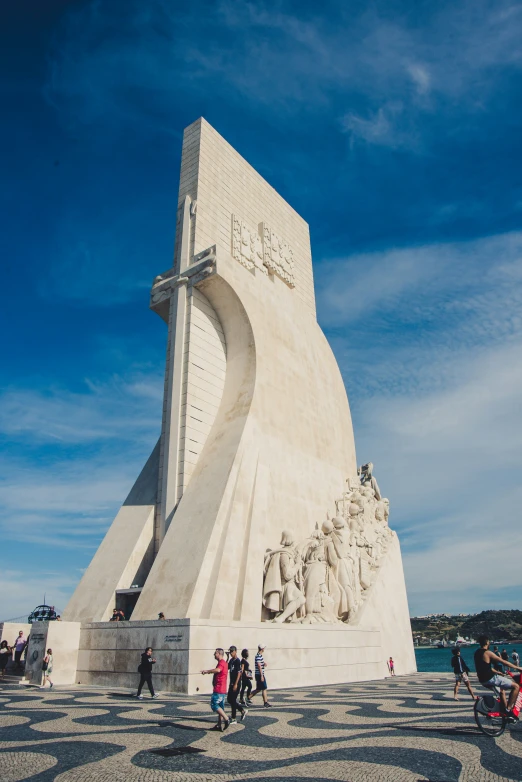 several people walk around the statue with its cross on top