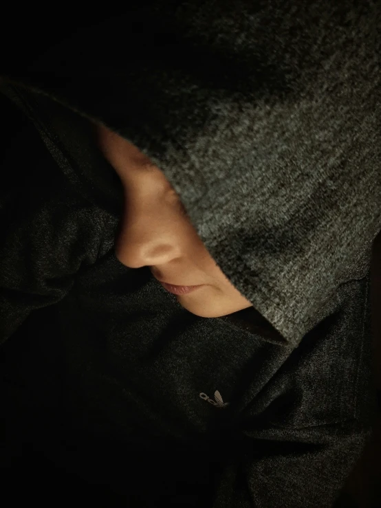 a person is sleeping with their head covered by dark blankets