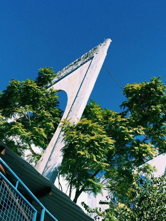 a man looking up at the top of a tall concrete structure with a triangular shape