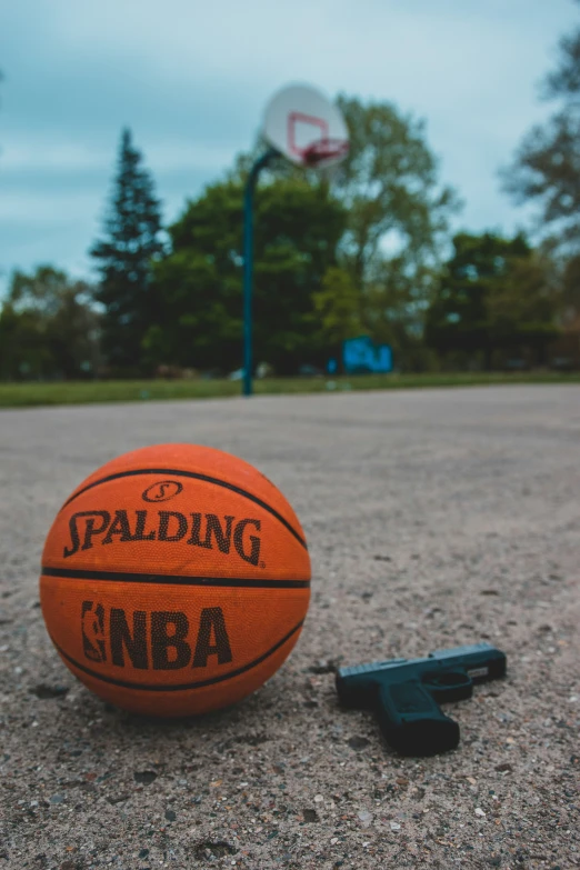 an orange ball laying on a road next to a black gun