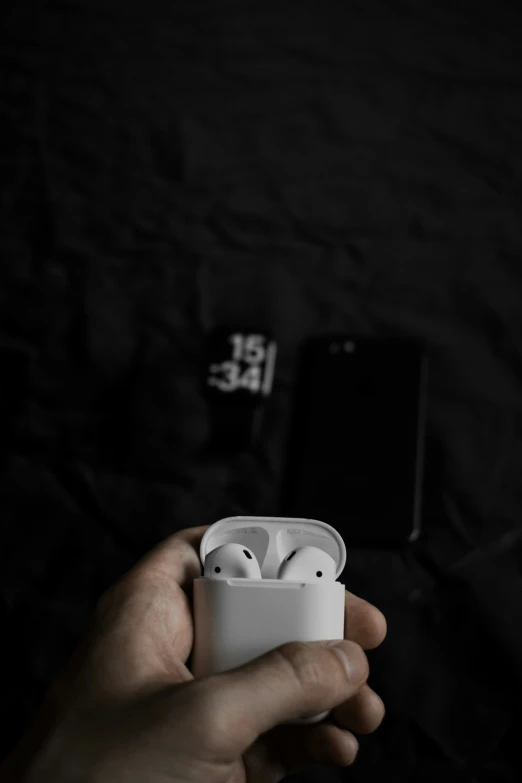 a hand holding an airpods that is being held by a person