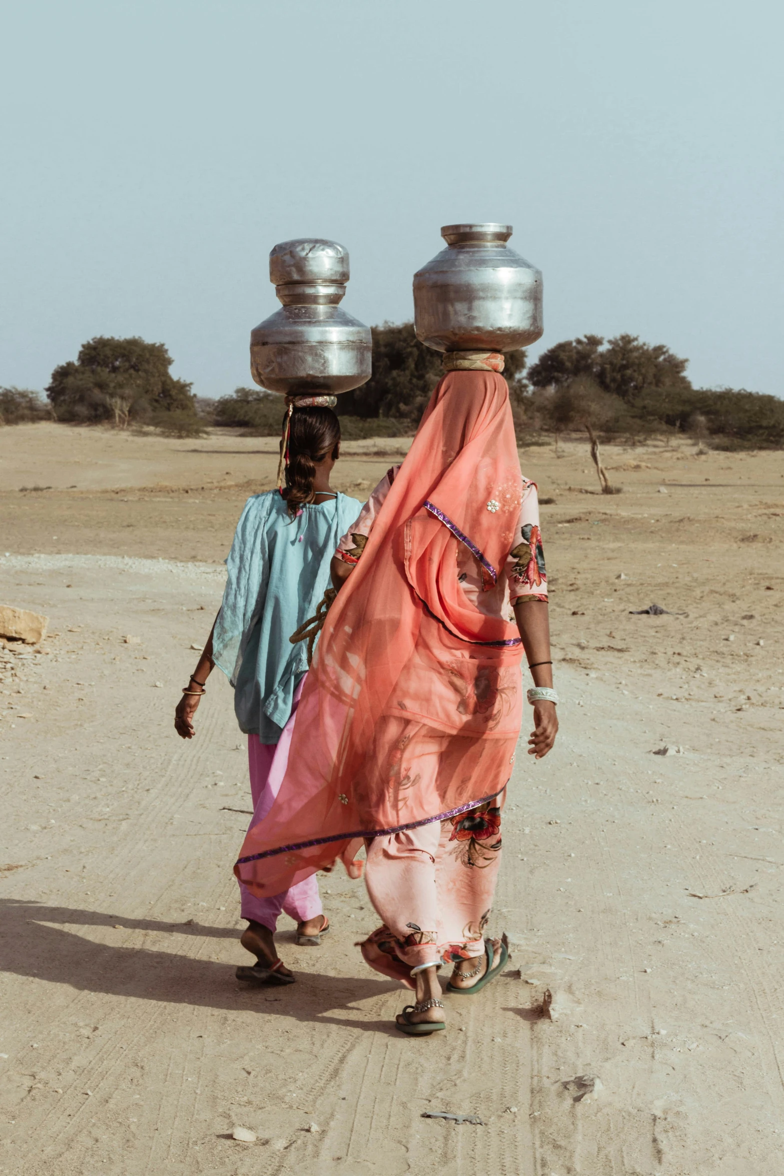 the two women are carrying water on their heads