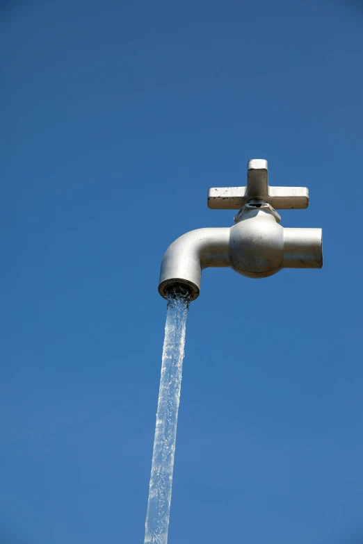 a single water faucet is leaking from the top of a pole