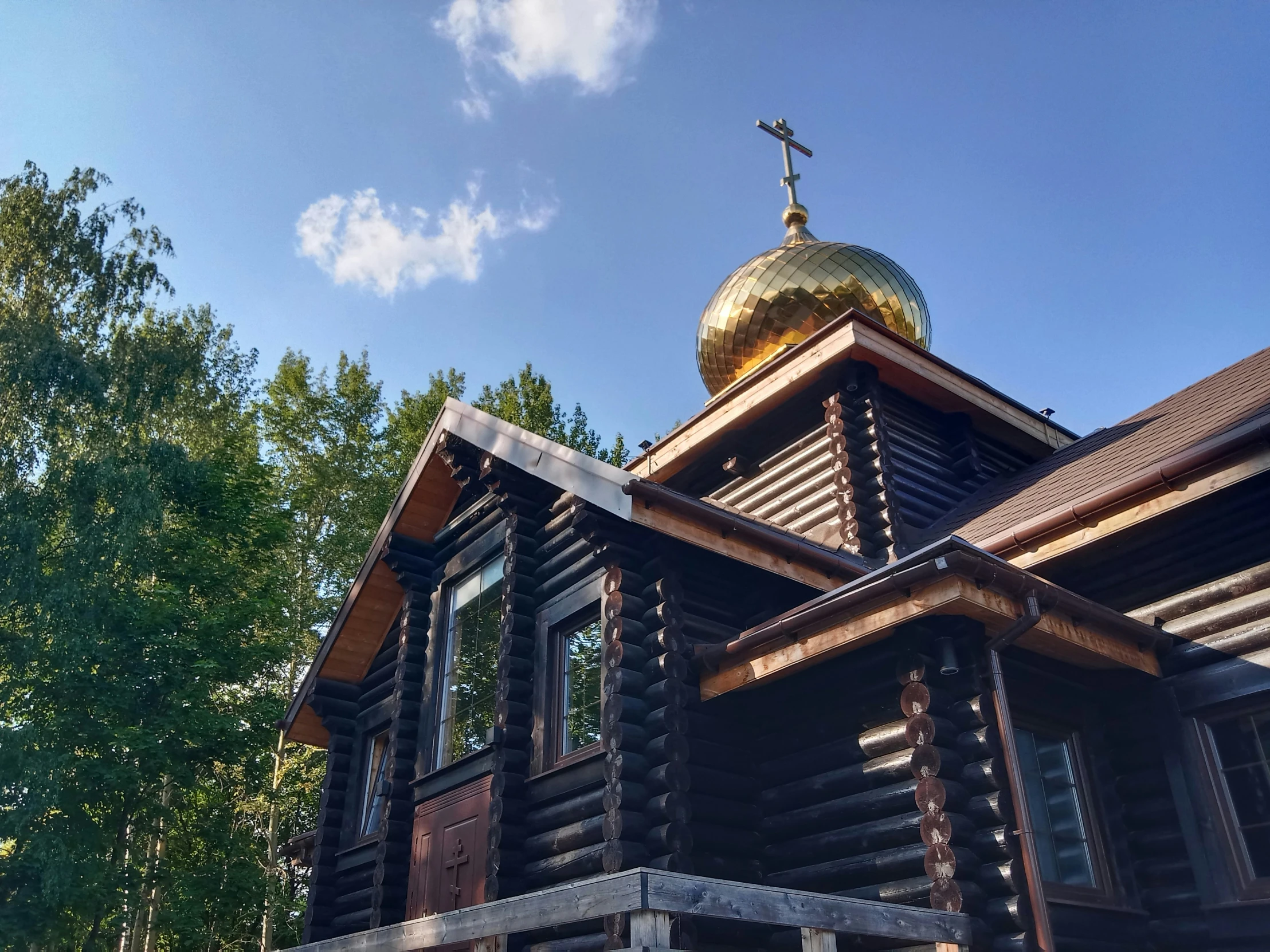 a church with a cross on top of it near trees