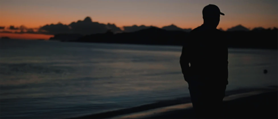 a man is standing on a beach near water