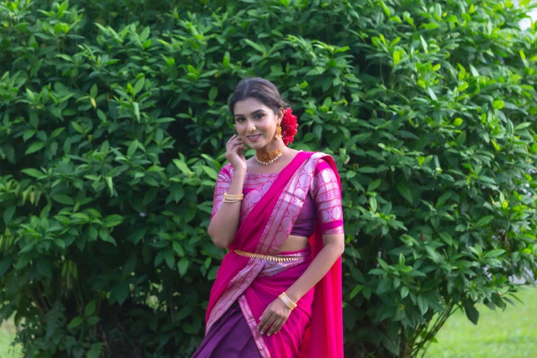 a beautiful young woman standing next to a tree talking on a phone