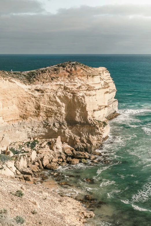 a man walking down a hill near the ocean