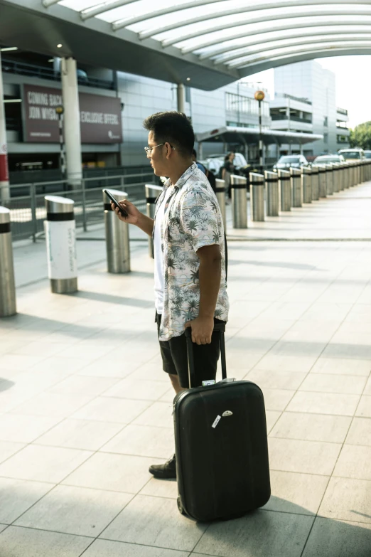 a man with a suitcase is looking at his cell phone