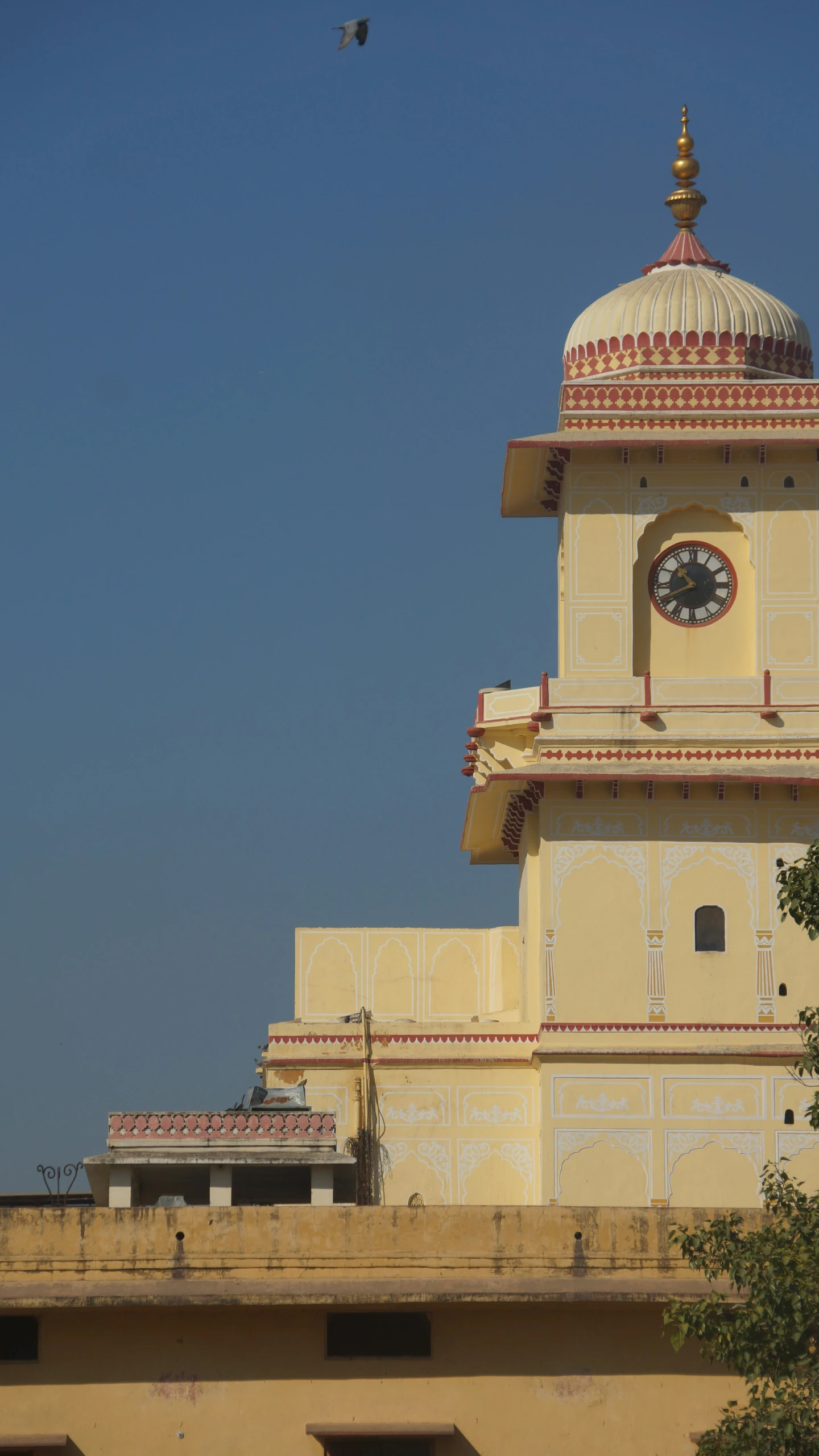 the clock tower is all white and has yellow and red trim