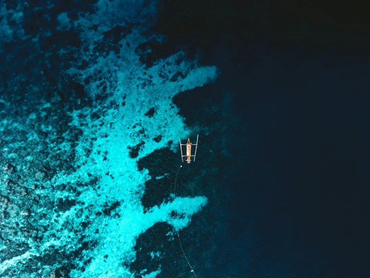 a small boat sailing in the middle of some deep blue water