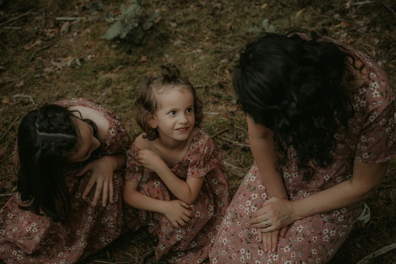 three small children sitting in a field smiling