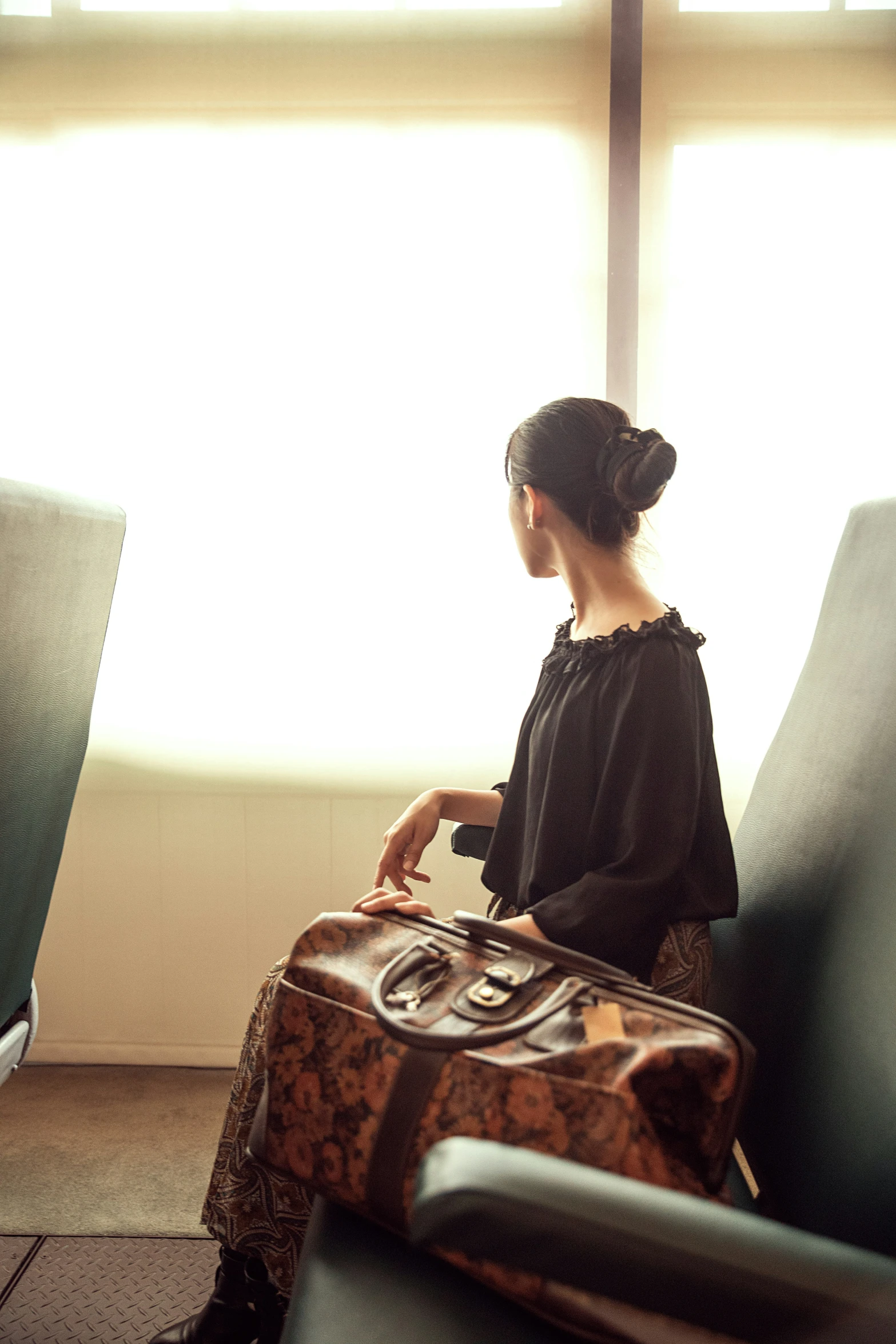 a woman is sitting with a suitcase in a waiting room