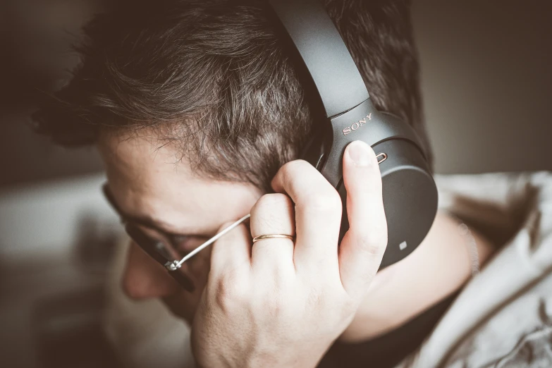 a man wearing glasses is holding up a phone to his ear