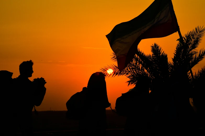 two people are holding a flag at sunset