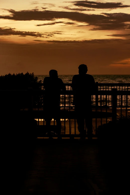 two people standing on a balcony looking out at the ocean