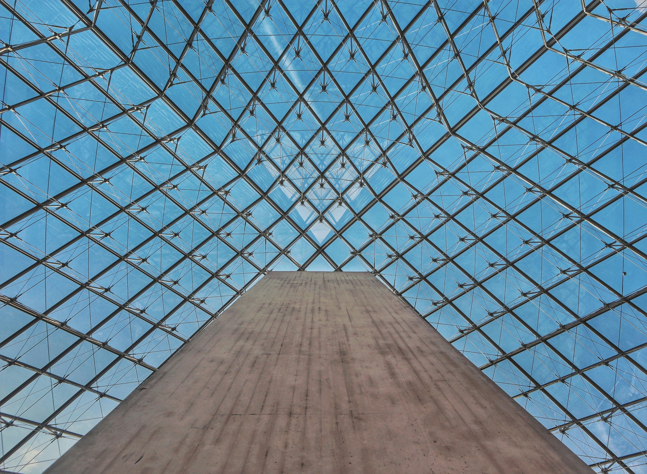 a very tall glass pyramid standing up against a blue sky