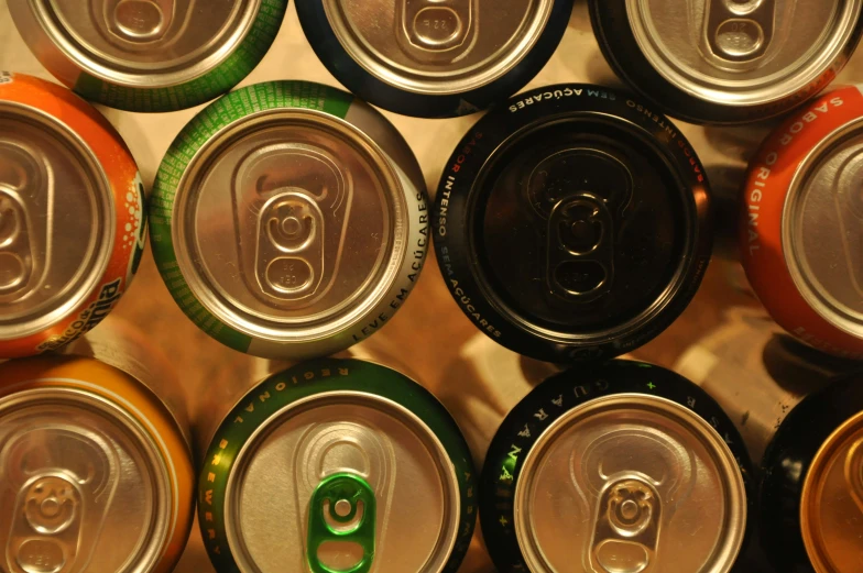 many soda cans with caps close together