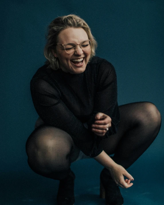 a woman laughing and crouching over soing blue
