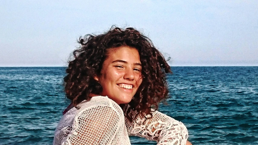 smiling woman sitting on a deck near the ocean