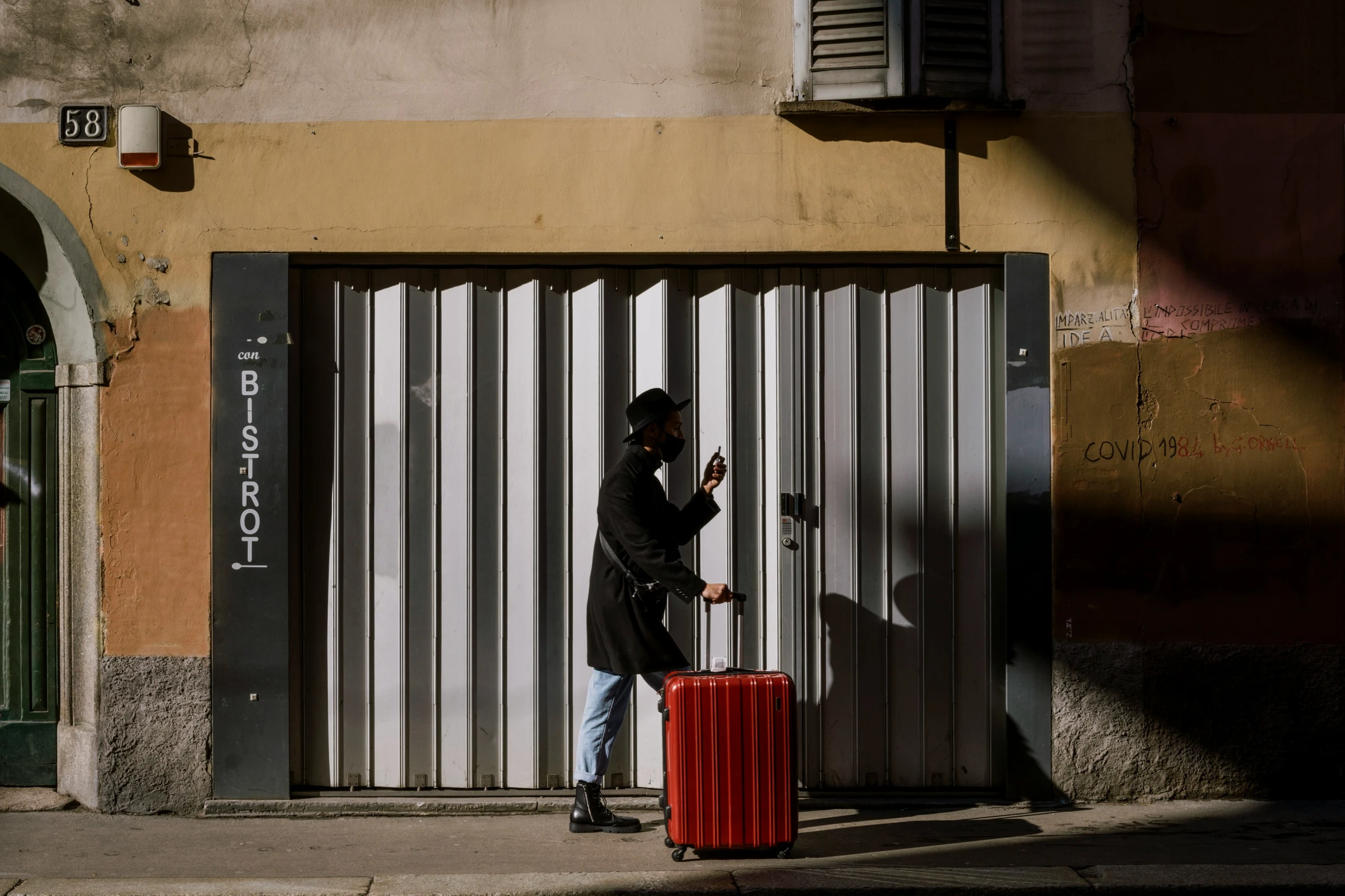 a man holding his arm up against a red suitcase