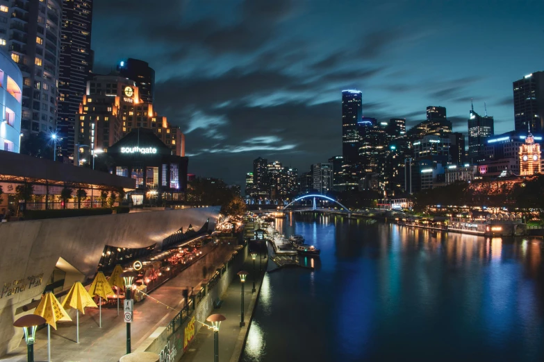 an evening view of city lights in front of the water