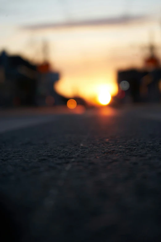 the sun is setting on an asphalt street