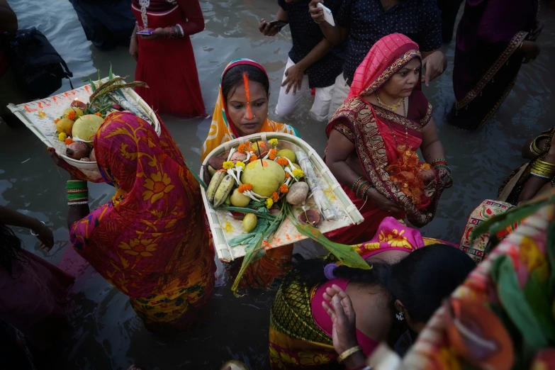 women in colorful dress and veils gathering around a lady holding a decoration item