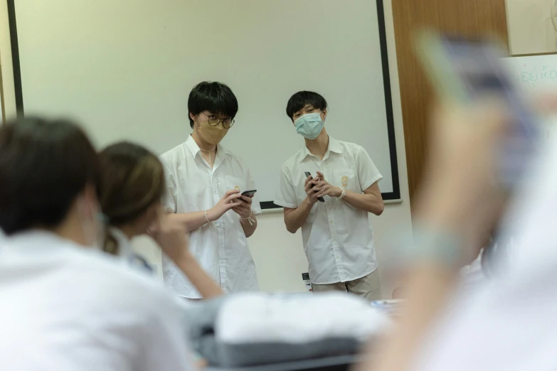 two people are wearing masks and looking at their phones