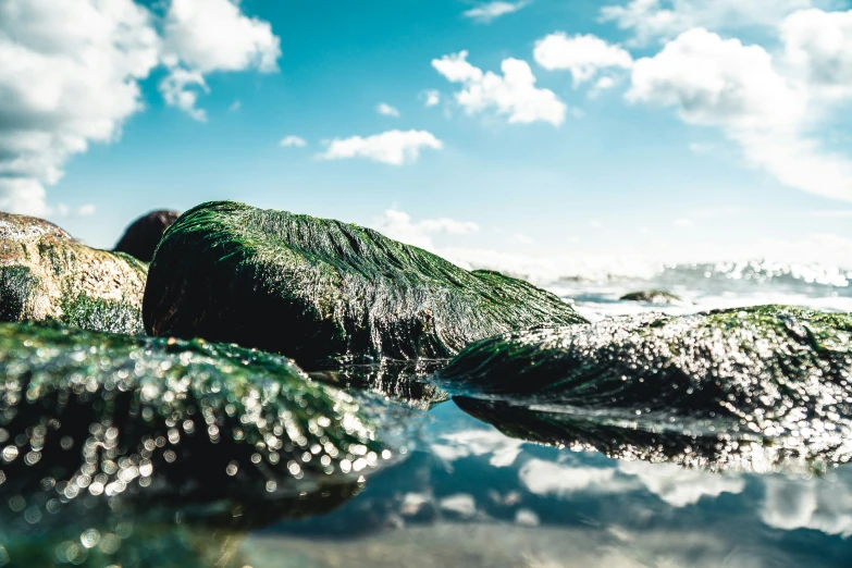 some rocks in the water under a blue cloudy sky