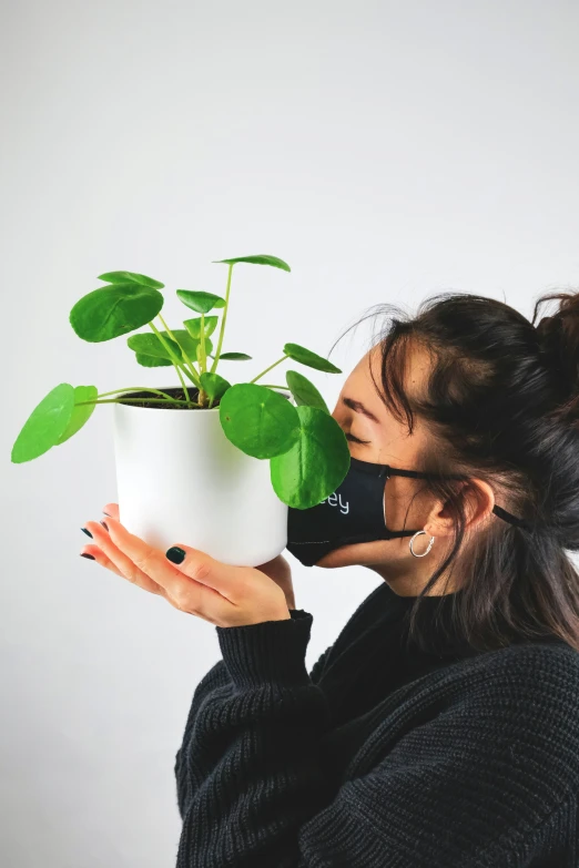 woman smelling potted plant with green leaves on the tip