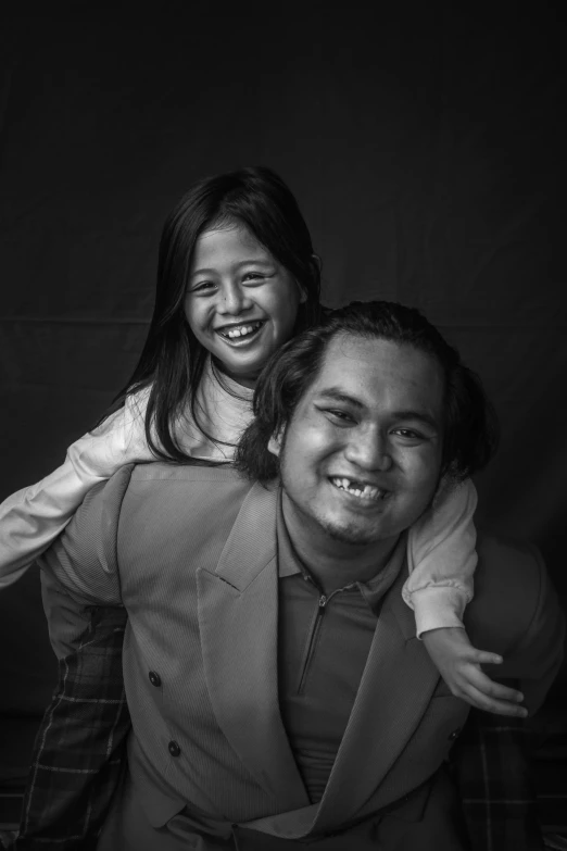 a little girl is holding her dad while he smiles