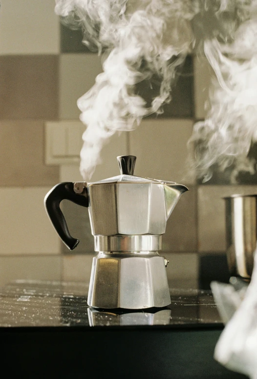 a coffee pot is on a stove with steam coming out