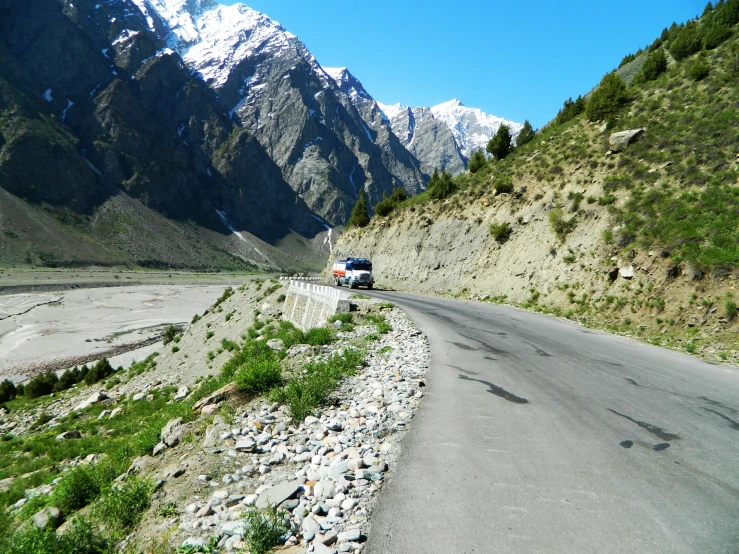 a blue truck driving along side of a rocky mountain