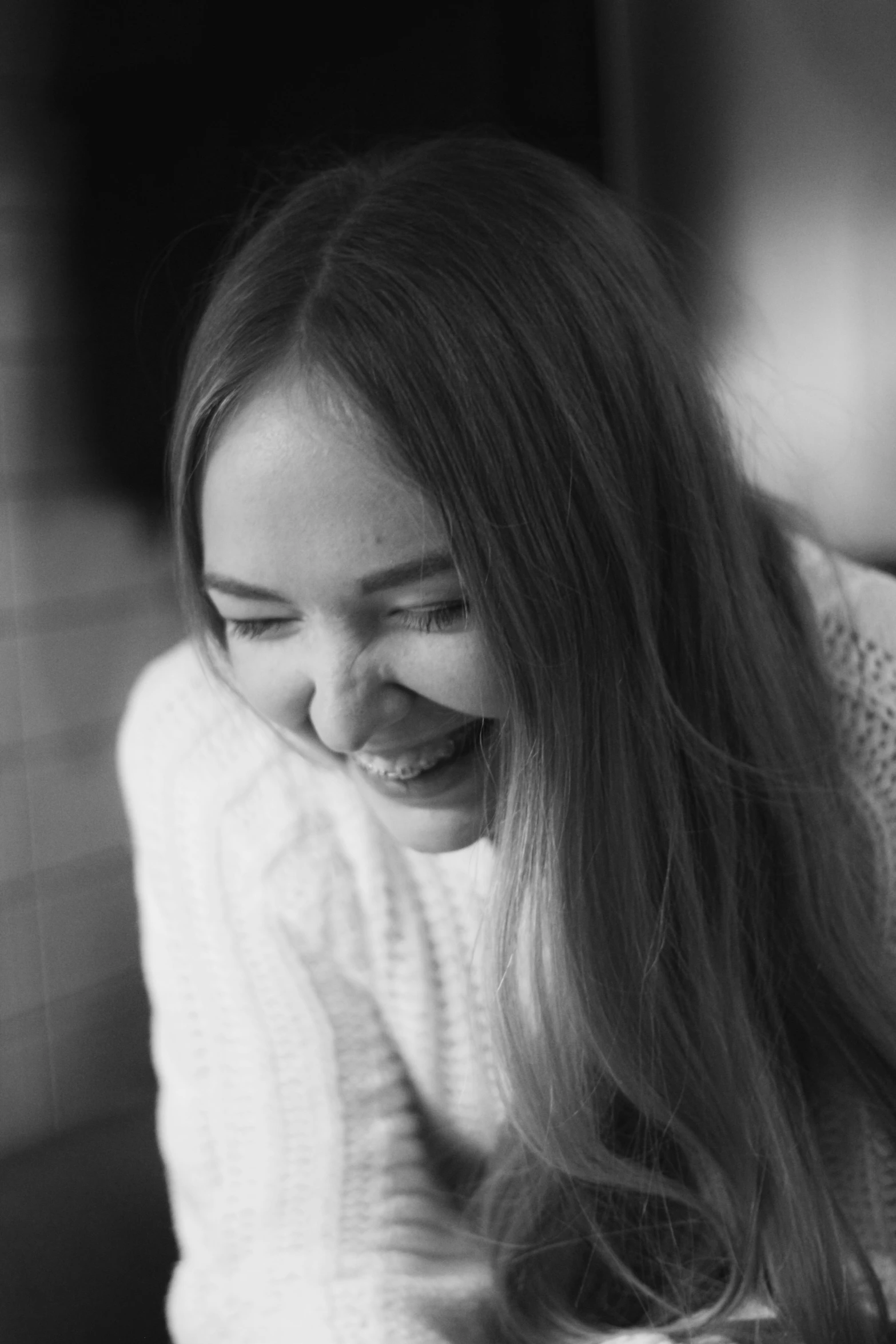 a girl laughing with long hair and wearing a sweater