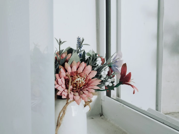 vase with different flowers on the windowsill