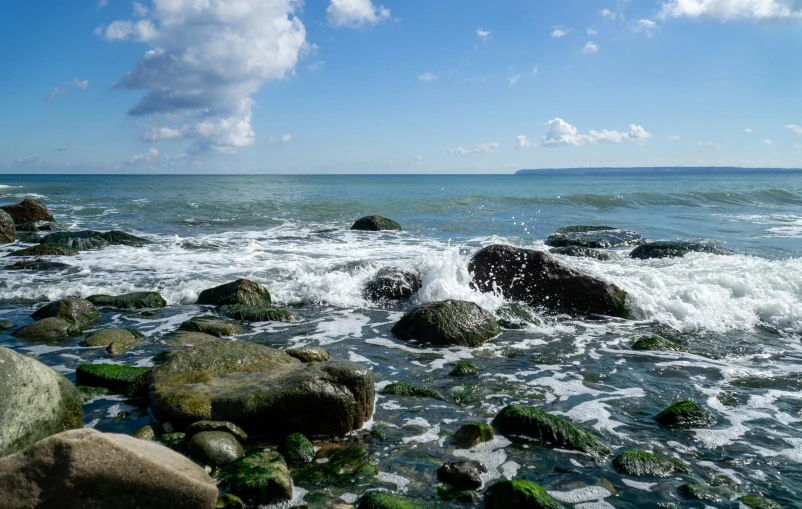 a rock beach with several large rocks sitting in the middle of it