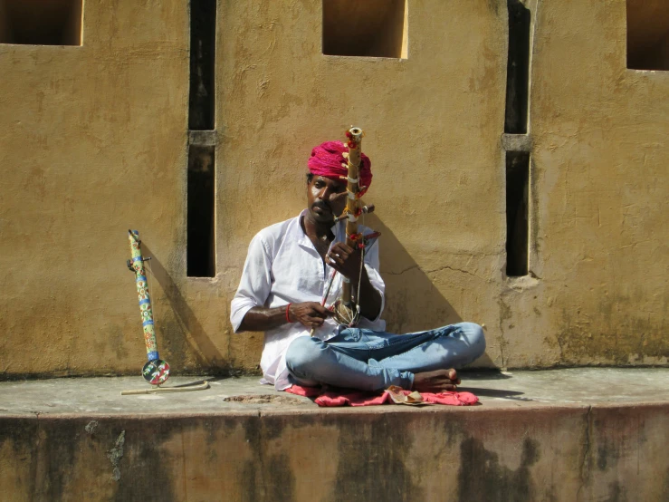 a man sits on the floor and plays with his instrument