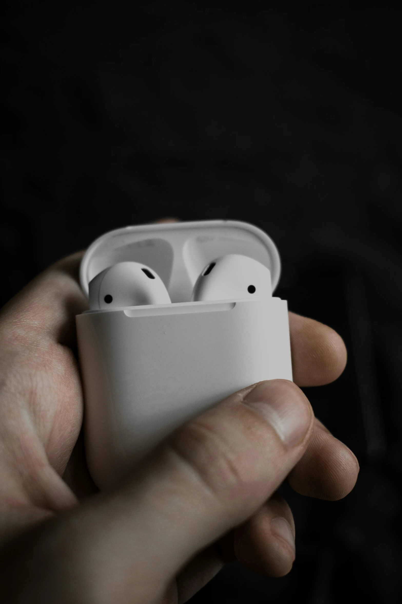 a person holding a couple of white ear buds