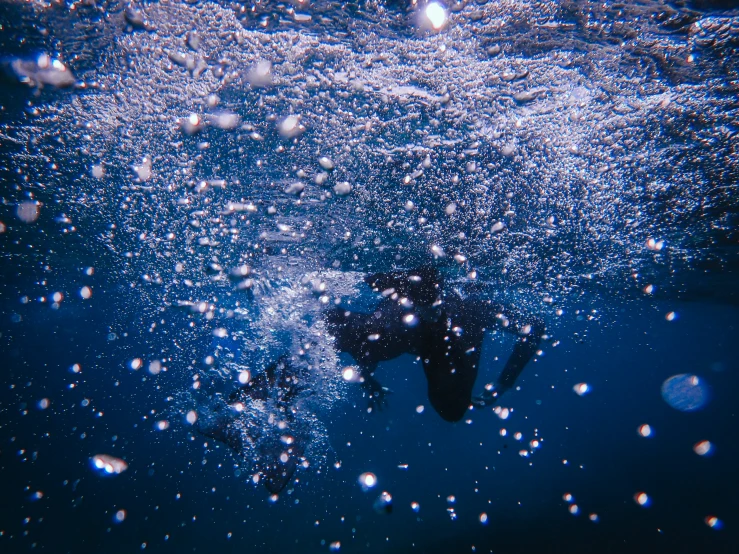 a man diving through a blue pool surrounded by bubbles