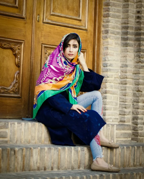 a woman in a colorful scarf sitting on a ledge