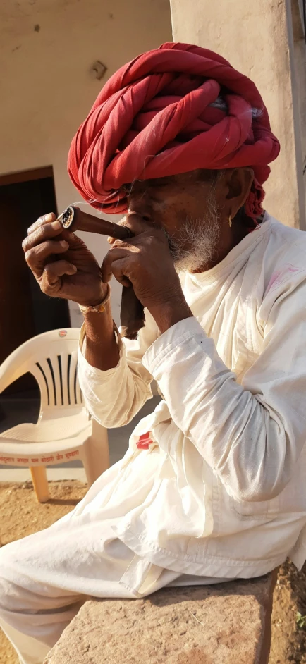 a man is sitting on a bench while smoking a cigarette